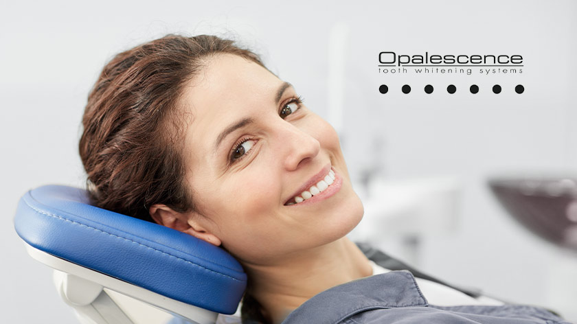 Lächelnde Patientin mit hellen Zähnen auf dem Behandlungsstuhl sitzend